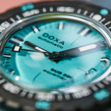 Close-up of a Doxa Sub Sea Automatic watch with a vibrant turquoise dial, black bezel, and silver-toned case.