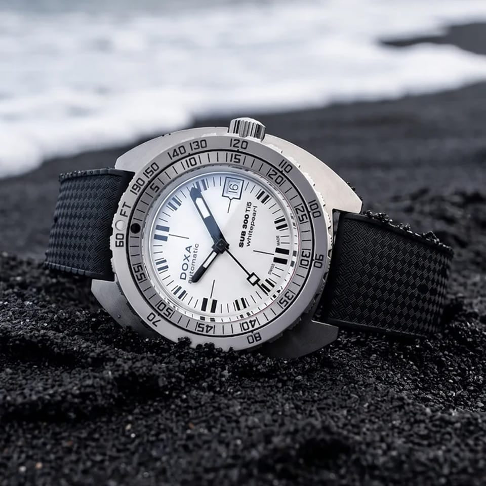 Side profile of DOXA SUB 300 Ti5 Whitepearl 42.5mm watch (Ref. 823.50.011.20) showing 13.4mm grade 5 titanium cushion case, screw-down crown, glass box sapphire crystal, and black rubber strap with folding clasp and wetsuit extension