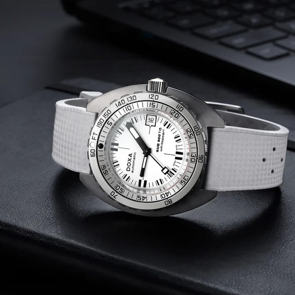 Front view of DOXA SUB 300 Ti5 Whitepearl watch, 42.5mm grade 5 titanium cushion case, white pearl dial with oversized orange minute hand, patented dual-scale dive bezel, screw-down crown, and white rubber strap with folding clasp — Ref. 823.50.011.23