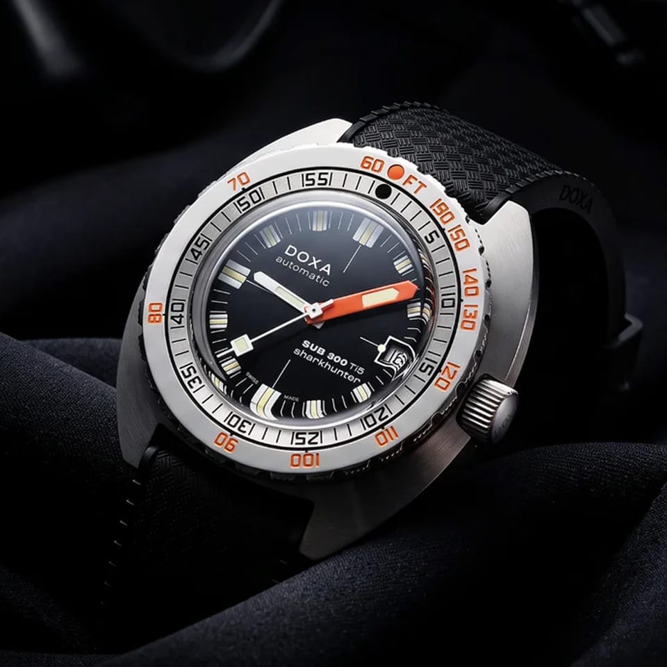 Front view of DOXA SUB 300 Ti5 Sharkhunter watch, 42.5mm grade 5 titanium cushion case, black dial with oversized orange minute hand, patented dual-scale dive bezel, screw-down crown, and black rubber strap with folding clasp — Ref. 823.50.101.20