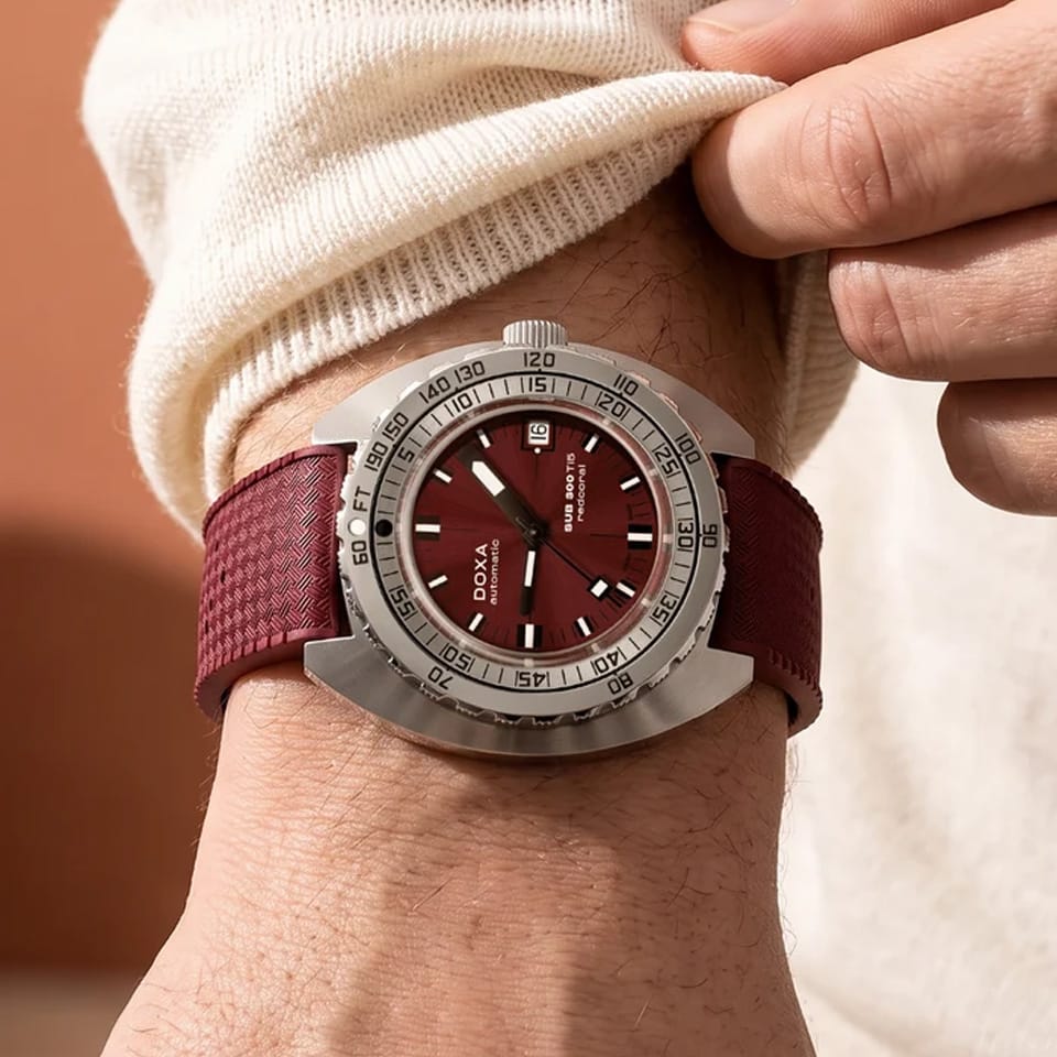 Front view of DOXA SUB 300 Ti5 Redcoral watch, 42.5mm grade 5 titanium cushion case, red coral dial with oversized orange minute hand, patented dual-scale dive bezel, screw-down crown, and red rubber strap with folding clasp — Ref. 823.50.161.22