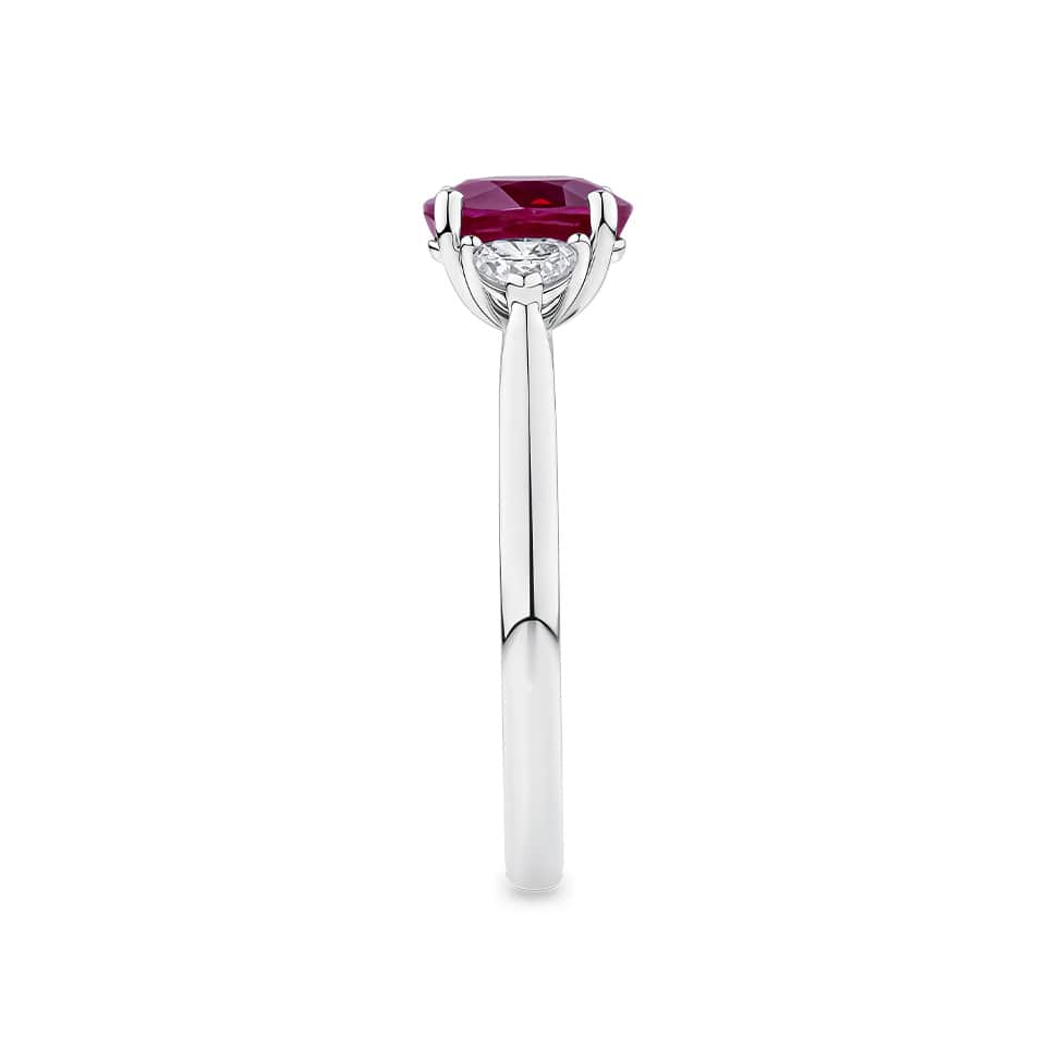 1.39 Carat Burmese Ruby and 0.36 Carat TW Diamond Trilogy Ring in 18ct White Gold — This side profile highlights the ring's tapered gallery and the heart-cut diamonds set with their points facing along the band. The 18ct white gold band maintains a slim, elegant silhouette from every angle.