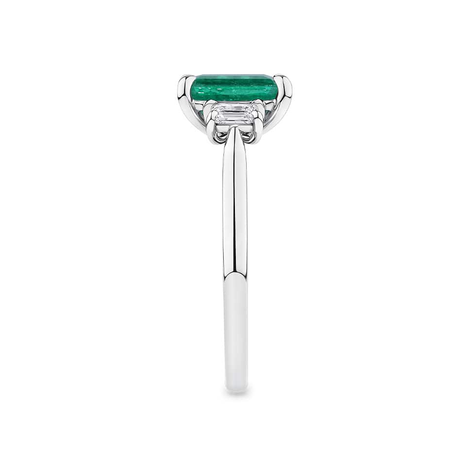 1.62 Carat Emerald and 0.40 Carat TW Diamond Trilogy Ring in 18ct White Gold — This side profile highlights the ring's tapered gallery and the natural emerald-cut diamonds set along each shoulder. The 18ct white gold band maintains a slim, elegant silhouette from every angle