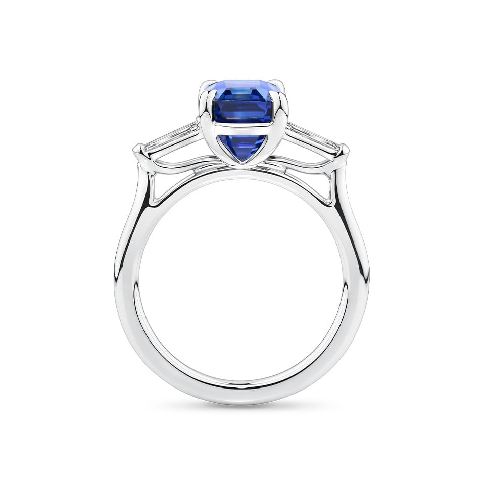 4.05 Carat Sapphire and 0.18 TW Carat Diamond Trilogy Ring in 18ct White Gold — Viewed from the front, the ring showcases its trilogy design with the emerald-cut sapphire set above tapered baguette diamonds on either side. The 18ct white gold setting frames the stones in a bright, cool tone.