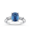 4.62 Carat Zircon and 0.36 Carat TW Diamond Trilogy Ring in 18ct White Gold — A 4.62 carat cushion-cut blue zircon sits at the centre of this trilogy design, flanked by two tapered baguette diamonds of G colour and VS clarity. The 18ct white gold setting provides a polished, cool contrast to the zircon's vivid blue hue.