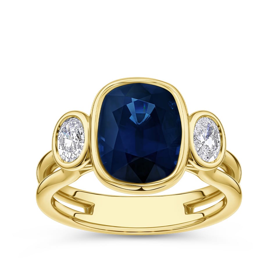5.63 Carat Oval Cut Sapphire and Diamond Trilogy Ring in 18ct yellow gold from Hardy Brothers Jewellers, shown front-on to display the scale of the centre sapphire.