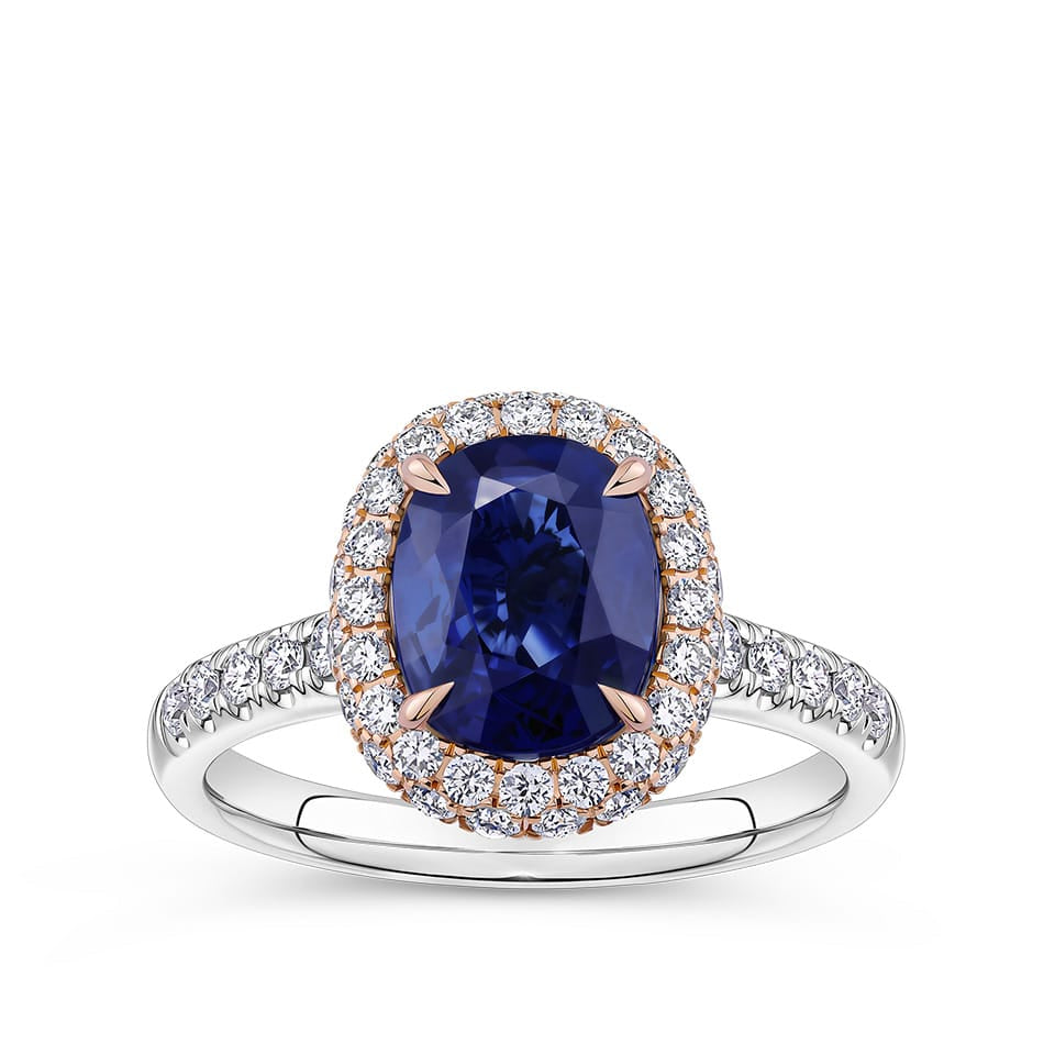2.50 Carat Sapphire and 0.70 Carat TW Diamond Halo Ring in 18ct Rose and White Gold — A 2.50 carat oval-cut sapphire is set within rose gold claws with intricate petal-like detailing, surrounded by a double halo of colourless natural diamonds of G colour and SI clarity. The white gold band features further diamonds along the shoulders.