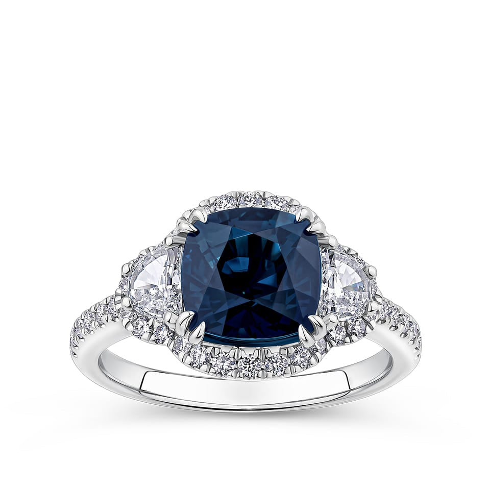 3.16 Carat Sapphire and 0.88 Carat TW Diamond Ring in 18ct White Gold — A certified 3.16 carat cushion-cut Australian sapphire is flanked by two half-moon cut natural diamonds and framed by a diamond halo, with further diamonds set along the band. The diamonds are G-H colour and VS-SI clarity.
