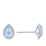 A pair of Pear Cut Aquamarine and Diamond Halo Stud Earrings in 18ct White Gold. shown on a plain white background with one earring facing forward and the other in side profile.