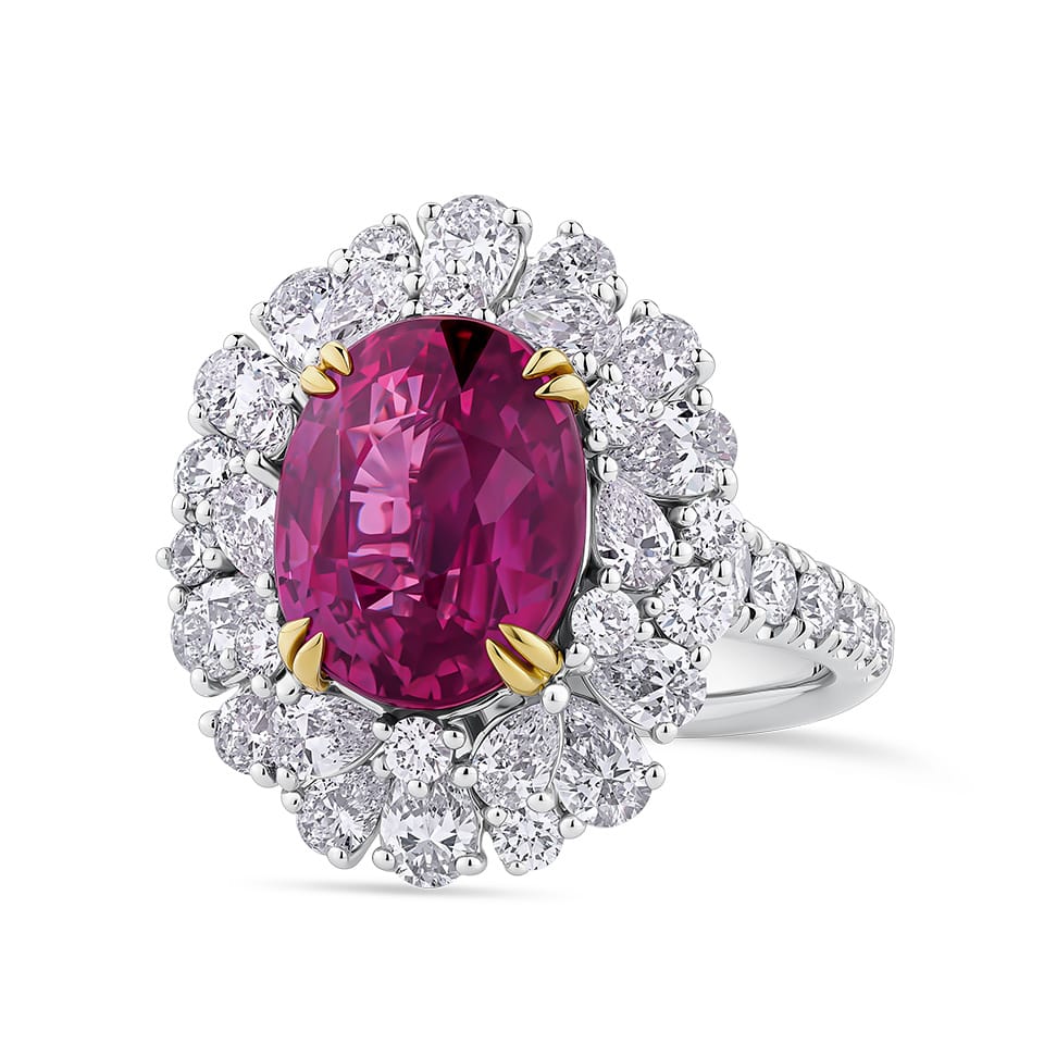 VAULT® 6.09 Carat TW Oval Cut Mozambique Ruby and 2.44 Carat TW Diamond Halo Ring in 18ct Yellow and White Gold — An oval cut Mozambique ruby sits at the centre, held by yellow gold claws within a scalloped double halo of pear and round brilliant cut diamonds. The diamond-set band continues the brilliance around the full shank.