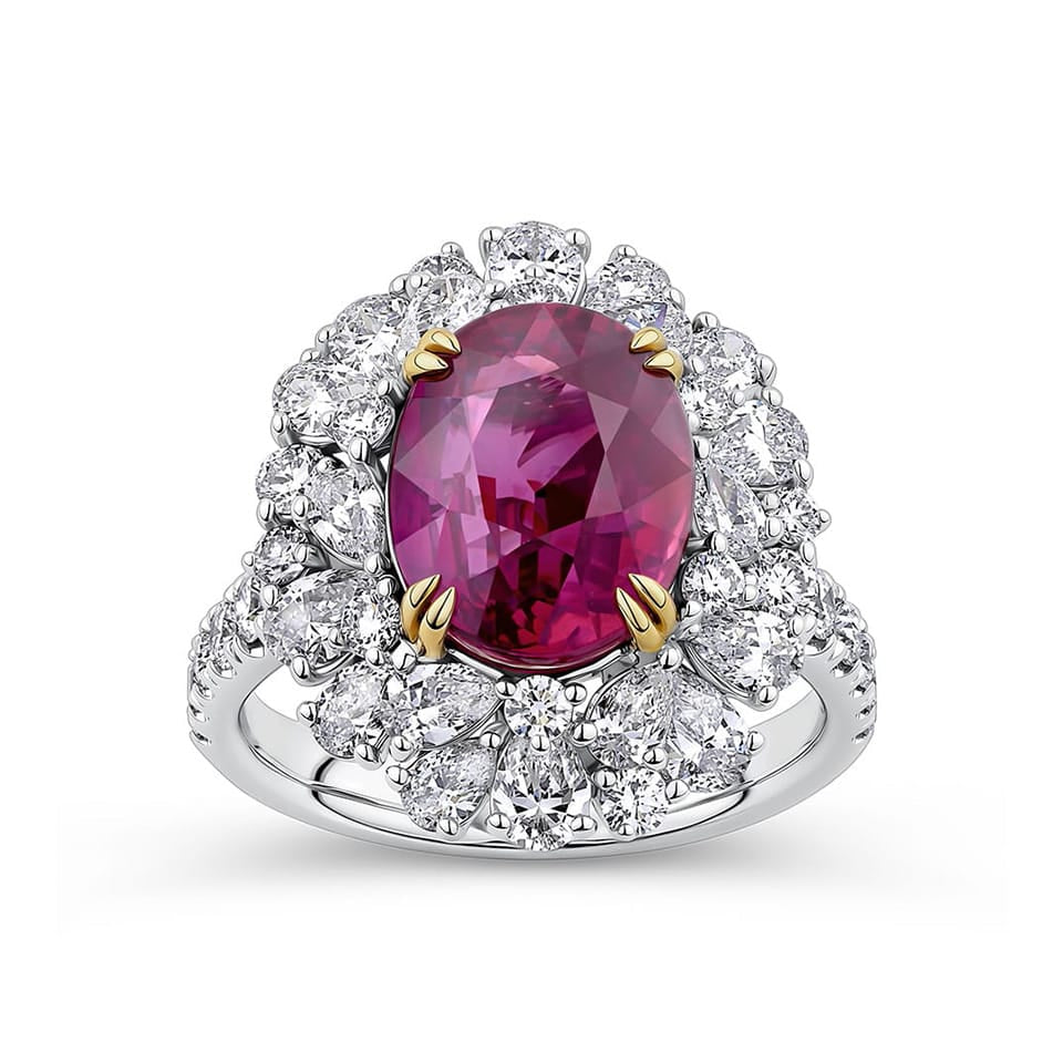 VAULT® 6.09 Carat TW Oval Cut Mozambique Ruby and 2.44 Carat TW Diamond Halo Ring in 18ct Yellow and White Gold — A close view reveals the ruby's rich, evenly saturated colour and clarity within its four-claw yellow gold setting. Pear-shaped diamonds radiate outward in a symmetrical double-halo design.