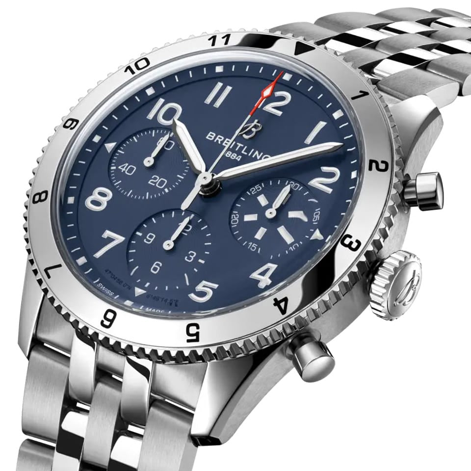 Breitling Classic AVI Automatic Chronograph 42mm Watch A233801A1C1A1 shows the bidirectional ratcheted bezel and cambered sapphire crystal from an angled perspective. The stainless steel bracelet connects seamlessly to the 42mm case.