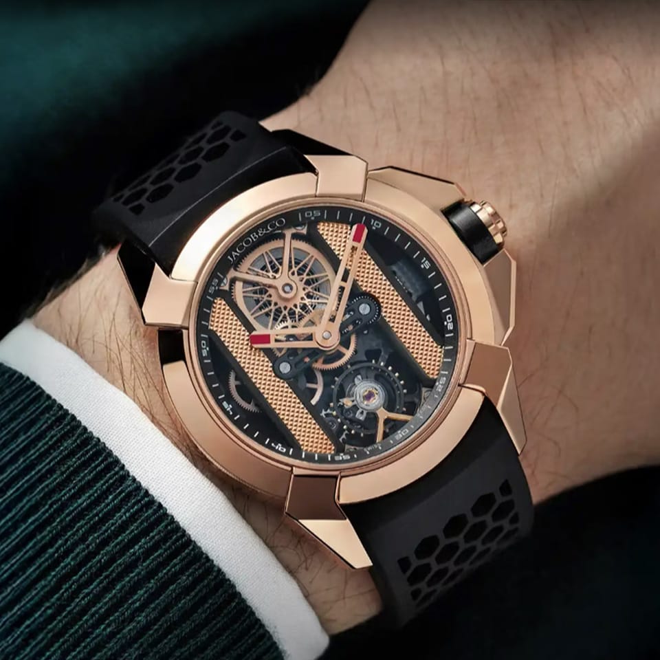 On wrist view of the Jacob & Co. Epic X Bridges 18K Rose Gold Black Manual Wind 44mm Watch, reference EX120.43.AB.AB.A, demonstrating the proportions of the 44mm case against the wrist. The Black Honeycomb Rubber strap contrasts against the 18K Rose Gold case and buckle.