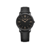 Front-facing view of the Baume & Mercier Classima M0A10762 men's watch, featuring a black dial with gilded Roman numerals, gilded leaf hands, date window at 3 o'clock, sandblasted stainless steel case with ADLC coating, and an interchangeable black Holland & Sherry fabric strap.
