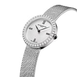 Three-quarter side view of the Baume & Mercier Joia M0A10850, highlighting the delicate 28mm lug-free round case profile, the 40 brilliant-cut diamond-set bezel catching the light, and the elegant polished stainless steel bracelet with its distinctive embossed crushed-link decoration flowing seamlessly from the case.