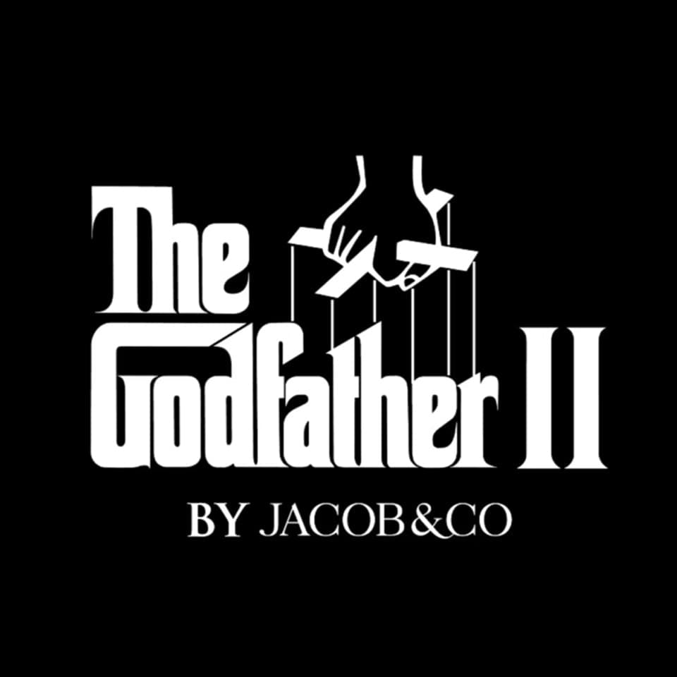 White 'The Godfather II' movie-style title graphic with puppet strings and hands above the text, plus 'BY JACOB&CO' below, on a solid black background.