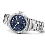 Three-quarter side view of the Baume & Mercier Riviera M0A10765, showcasing the slim 33mm twelve-sided case profile, the brilliant-cut diamond-set bezel sparkling from this angle, the domed scratch-resistant sapphire crystal above the night blue dial, and the polished and satin-finished stainless steel bracelet flowing seamlessly from the case.