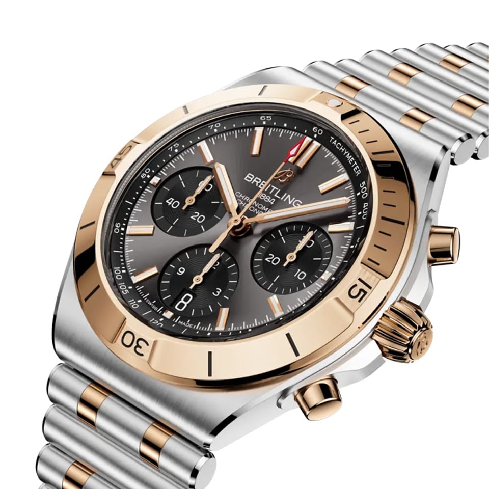 Breitling Chronomat B01 42mm — three-quarter view showcasing black dial, two-tone 18k red gold and steel case with rider tab bezel and integrated Rouleaux bracelet