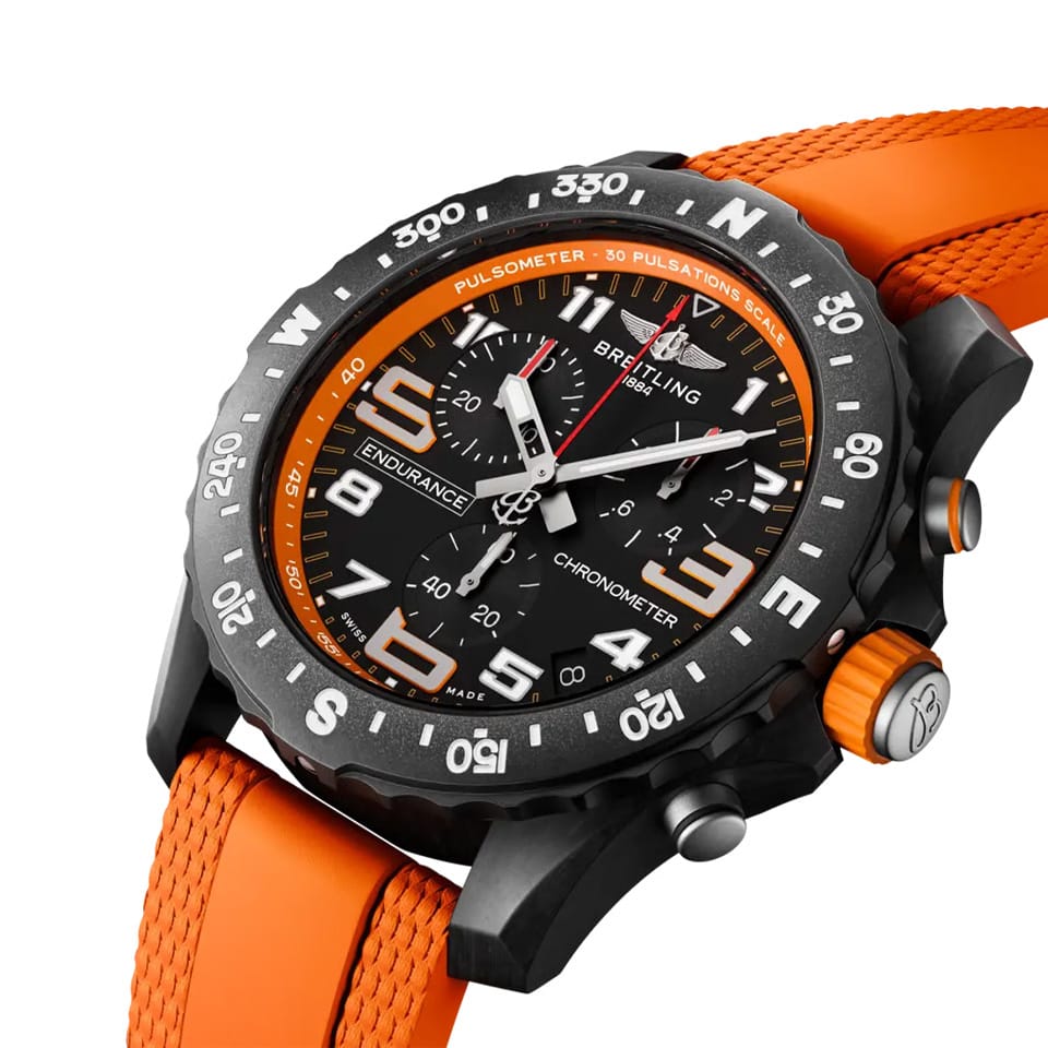 Breitling Endurance Pro Quartz Chronograph 44mm Watch X82310A51B1S2 shows the sapphire crystal and textured Breitlight® finish from an angled perspective. The orange rubber strap curves into the 44mm case for an athletic, everyday-wear profile.