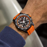 Breitling Endurance Pro Quartz Chronograph 44mm Watch X82310A51B1S2 is shown worn on the wrist, highlighting the proportions of its 44mm case and orange rubber strap. This chronograph is powered by the COSC-certified SuperQuartz™ Caliber 82, roughly ten times more accurate than standard quartz.