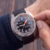 Front view of DOXA SUB 300 Ti5 Sharkhunter watch, 42.5mm grade 5 titanium cushion case, black dial with oversized orange minute hand, patented dual-scale dive bezel, screw-down crown, and black rubber strap with folding clasp — Ref. 823.50.101.20