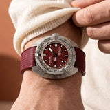 Front view of DOXA SUB 300 Ti5 Redcoral watch, 42.5mm grade 5 titanium cushion case, red coral dial with oversized orange minute hand, patented dual-scale dive bezel, screw-down crown, and red rubber strap with folding clasp — Ref. 823.50.161.22