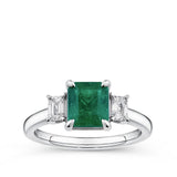 1.81 Carat Emerald and 0.30 Carat TW Diamond Trilogy Ring in 18ct White Gold — A 1.81 carat emerald-cut emerald sits at the centre of this trilogy design, flanked by two natural emerald-cut diamonds of H-I colour and VS-SI clarity. The 18ct white gold setting provides a polished, cool contrast to the emerald's rich green hue.