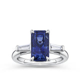 4.05 Carat Sapphire and 0.18 TW Carat Diamond Trilogy Ring in 18ct White Gold — A certified 4.05 carat emerald-cut natural blue sapphire sits at the centre of this trilogy design, flanked by two tapered baguette diamonds of G colour and VS clarity. The 18ct white gold setting provides a polished, cool contrast to the sapphire's deep blue hue.