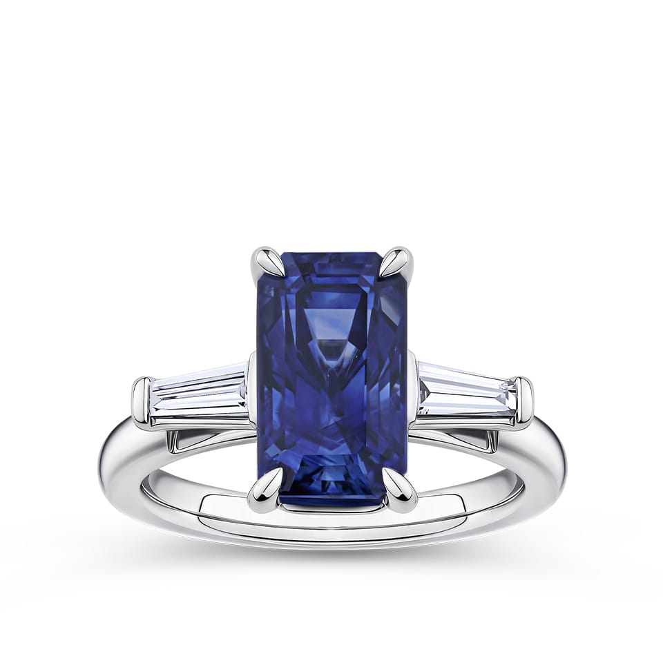 4.05 Carat Sapphire and 0.18 TW Carat Diamond Trilogy Ring in 18ct White Gold — A certified 4.05 carat emerald-cut natural blue sapphire sits at the centre of this trilogy design, flanked by two tapered baguette diamonds of G colour and VS clarity. The 18ct white gold setting provides a polished, cool contrast to the sapphire's deep blue hue.
