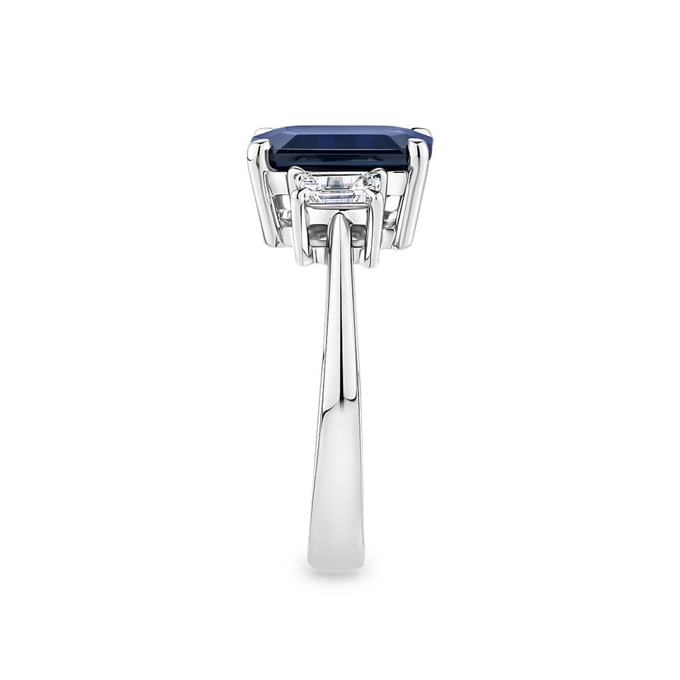 3.68 Carat Sapphire and 0.42 Carat TW Diamond Trilogy Ring in 18ct White Gold — This side profile highlights the ring's claw-set gallery and the natural emerald-cut diamonds set along each shoulder. The 18ct white gold band maintains a slim, elegant silhouette from every angle.
