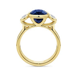 Angled view of the Sapphire and Diamond Trilogy Ring in 18ct yellow gold by Hardy Brothers, highlighting the bezel-set sapphire and diamond side stones.