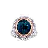 7.66 Carat Sapphire and 1.04 Carat TW Diamond Halo Ring in 18ct Rose and White Gold — A 7.66 carat cushion-cut blue sapphire is encircled by an inner halo of 28 natural pink diamonds in rose gold and an outer halo of 38 round-cut natural diamonds of G colour and SI clarity in white gold. The band features grain-set white diamonds along the shoulders.