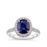2.50 Carat Sapphire and 0.70 Carat TW Diamond Halo Ring in 18ct Rose and White Gold — A 2.50 carat oval-cut sapphire is set within rose gold claws with intricate petal-like detailing, surrounded by a double halo of colourless natural diamonds of G colour and SI clarity. The white gold band features further diamonds along the shoulders.