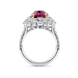VAULT® 6.09 Carat TW Oval Cut Mozambique Ruby and 2.44 Carat TW Diamond Halo Ring in 18ct Yellow and White Gold — Viewed at an angle, the ruby's deep crimson hue is framed by tiers of pear and round brilliant cut diamonds forming a flower-like halo. Yellow gold claw settings contrast against the white gold mounting.