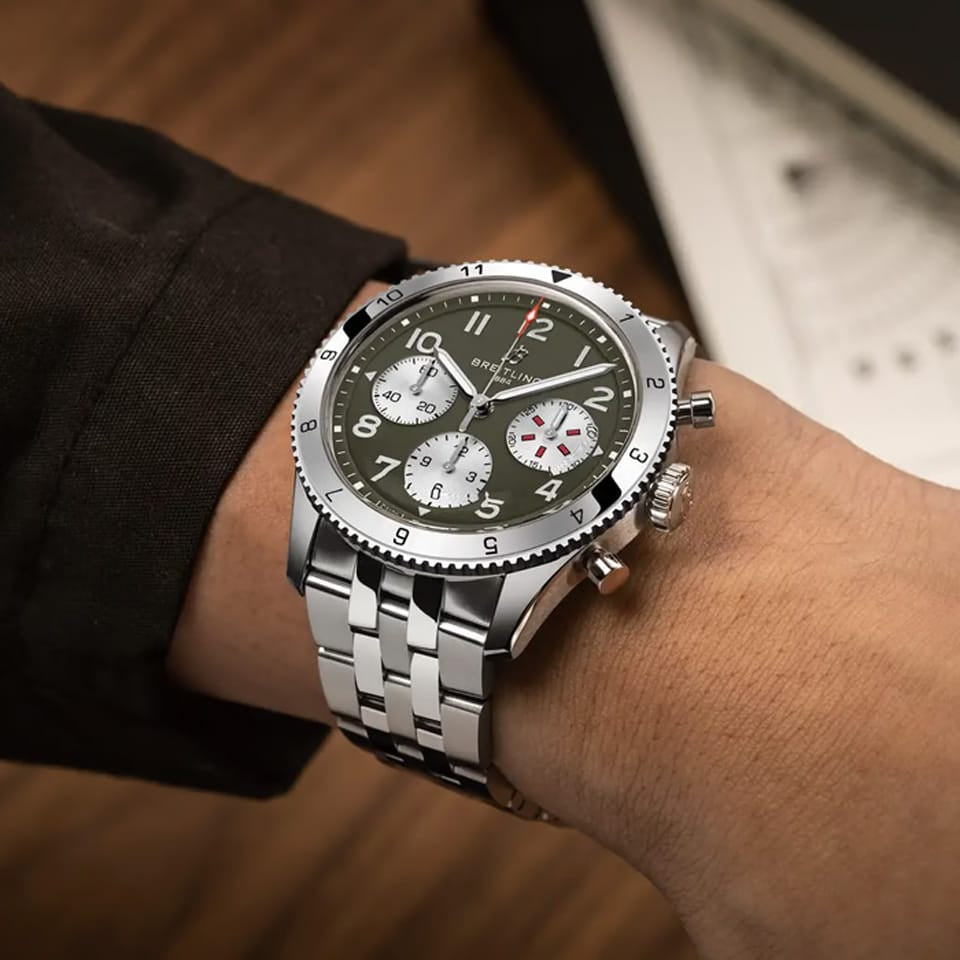 Breitling Classic AVI Automatic Chronograph 42mm Watch A233802A1L1A1 is shown worn on the wrist, highlighting the proportions of its 42mm case and stainless steel bracelet. This COSC-certified chronograph is powered by the Breitling Caliber 23 with an approximate 48-hour power reserve.