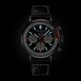 Breitling Top Time Deus B01 Chronograph 41mm Watch AB01765A1B1X1 shows the luminous properties of its dial markers and lightning-bolt-shaped chronograph hand in low light. The Deus emblem and squircle subdials remain legible against the illuminated black dial.
