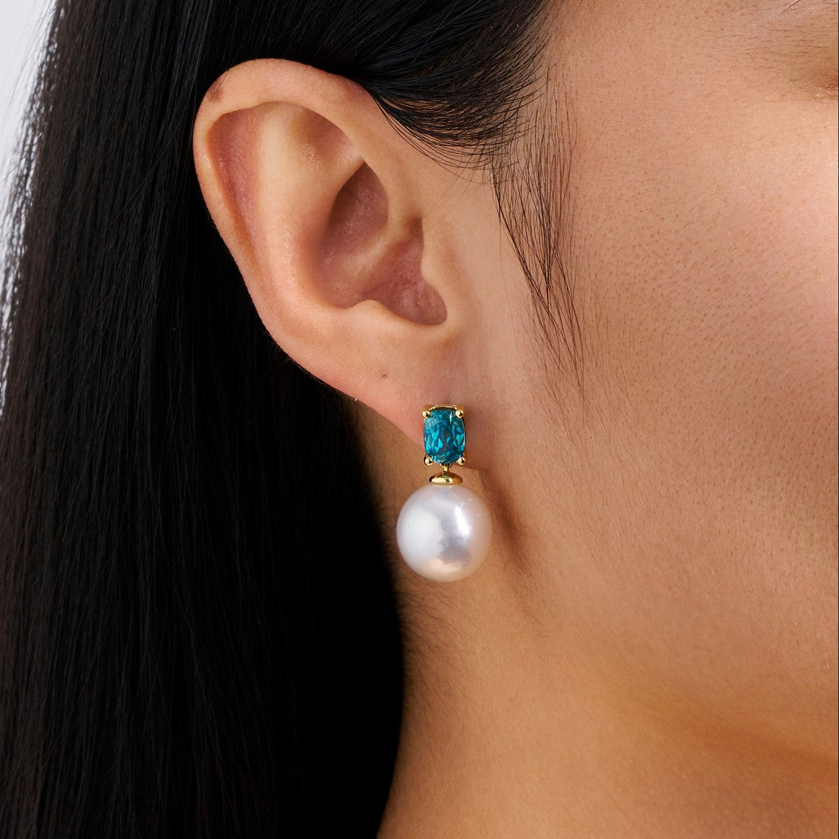 Close-up detail of the South Sea Pearl and Zircon Stud Earrings in 18ct yellow gold by Hardy Brothers, highlighting the cushion cut blue zircon and the 12mm South Sea pearl.