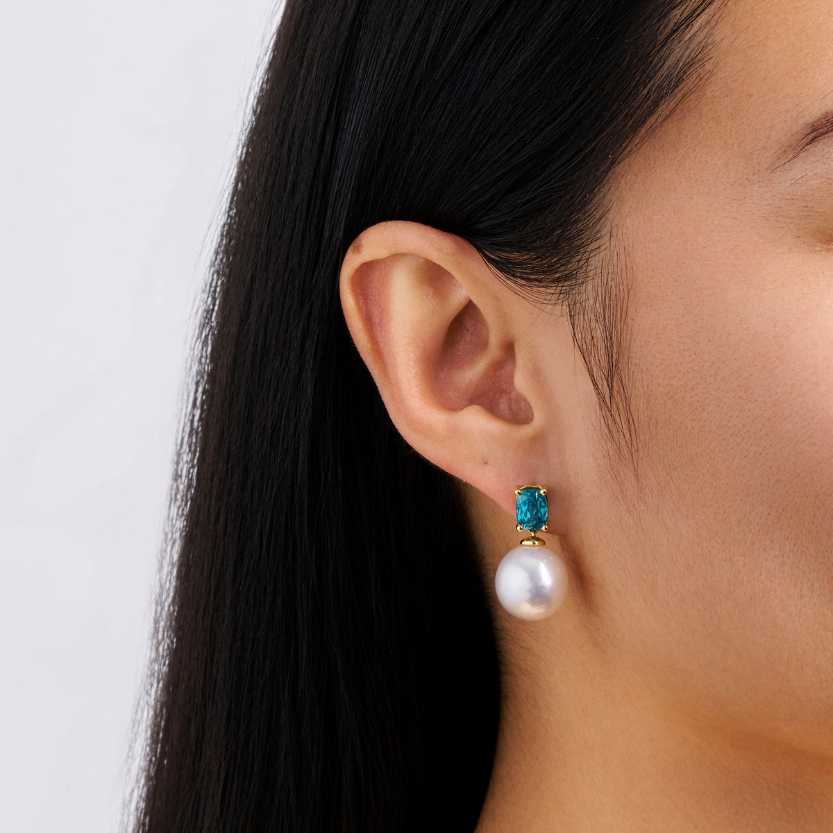Close-up detail of the South Sea Pearl and Zircon Stud Earrings in 18ct yellow gold by Hardy Brothers, highlighting the cushion cut blue zircon and the 12mm South Sea pearl.