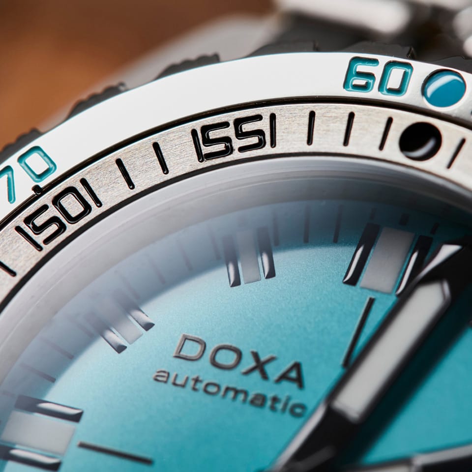 Close-up of a DOXA SUB 300T Aquamarine Automatic 42.50mm Watch 840.10.241.10 with a turquoise dial, silver-toned case, and a black and silver rotating bezel with turquoise numerals.