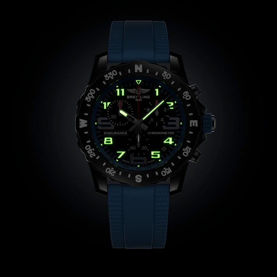 Breitling Endurance Pro Quartz Chronograph 44mm Watch X82310281B1S2 shows the luminous properties of its dial markers and hands in low light. The black dial and blue accents remain legible against the illuminated Breitlight® case in dark conditions.