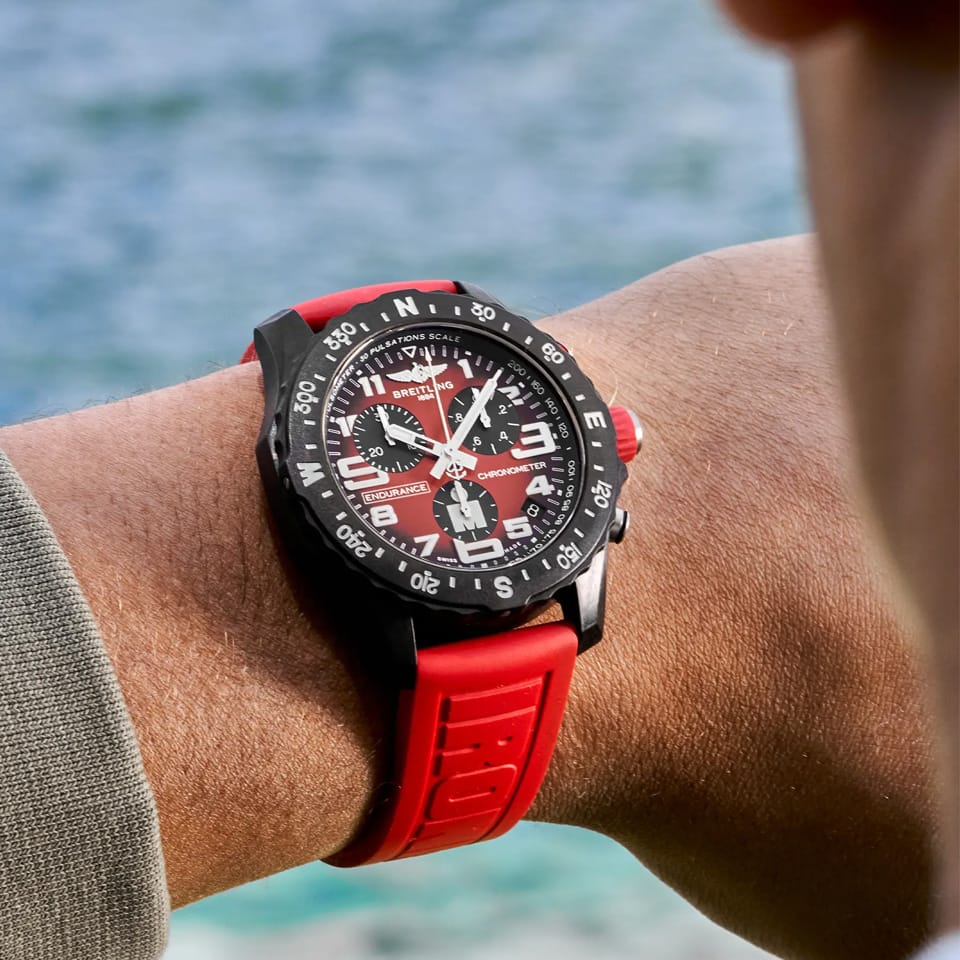 Breitling Endurance Pro Quartz Chronograph 44mm Watch X823109A1K1S1 is shown worn on the wrist, highlighting the proportions of its 44mm case and IRONMAN® branded strap. This chronograph is powered by the COSC-certified SuperQuartz™ Caliber 82, roughly ten times more accurate than standard quartz.