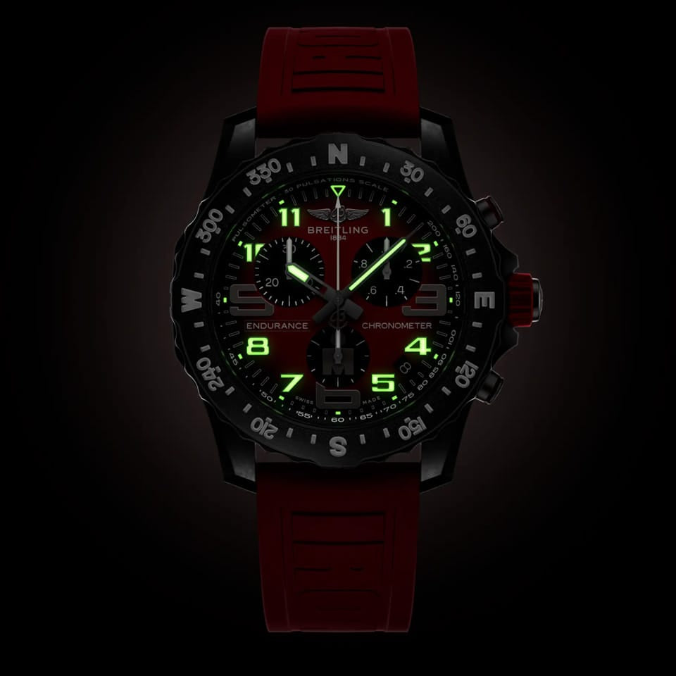 Breitling Endurance Pro Quartz Chronograph 44mm Watch X823109A1K1S1 shows the luminous properties of its dial markers and hands in low light. The red IRONMAN® dial remains legible against the illuminated Breitlight® case in dark conditions.