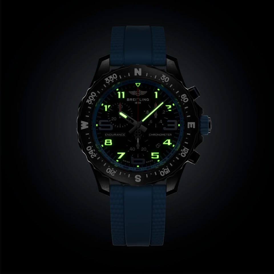 Breitling Endurance Pro Quartz Chronograph 38mm Watch X83310281B1S1 shows the luminous properties of its dial markers and hands in low light. The black dial and blue accents remain legible against the illuminated Breitlight® case in dark conditions.