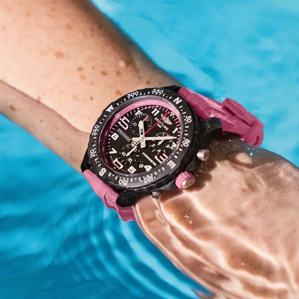 Breitling Endurance Pro Quartz Chronograph 38mm Watch X83310D41B1S1 is shown worn on the wrist, highlighting the proportions of its 38mm case and pink rubber strap. This chronograph is powered by the COSC-certified SuperQuartz™ Caliber 83, roughly ten times more accurate than standard quartz.