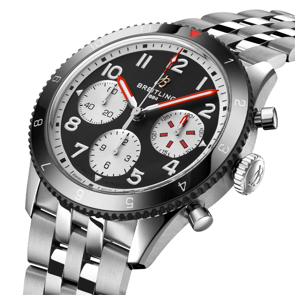 Breitling Classic AVI Automatic Chronograph 42mm Watch Y233801A1B1A1 shows the bidirectional ratcheted bezel and cambered sapphire crystal from an angled perspective. The stainless steel bracelet connects seamlessly to the 42mm case.