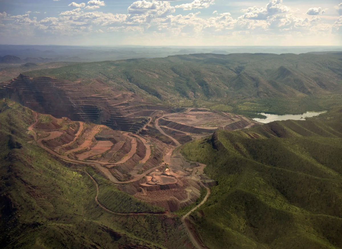 Aerial view of a mining operation in a hilly landscape with a river.